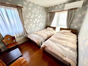 广岛lifeone club的一间卧室配有两张床和椅子