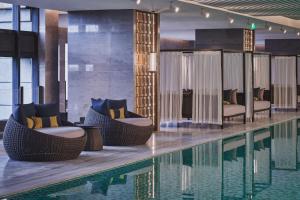 昆山HUALUXE Kunshan Huaqiao, an IHG Hotel - F1 Racing Preferred Hotel的游泳池旁设有藤椅和椅子的游泳池