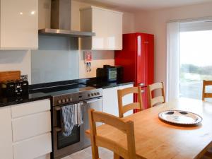 基斯高地Morys Cottage的厨房配有桌子和红色冰箱