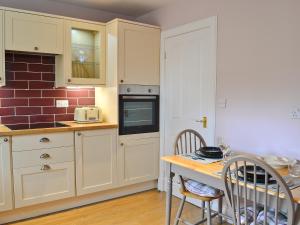 莫法特Roseburn Cottage的厨房配有白色橱柜和桌椅