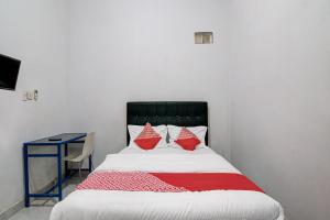 杜迈OYO 92111 Dinda Homestay Syariah的一间卧室配有一张带红色枕头的床和一张书桌
