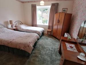 PentrichThe Bungalow的一间卧室设有两张床、一个梳妆台和窗户。
