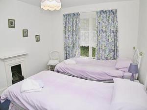 WithycombeTacker Street Cottage的一间卧室设有两张床、一个壁炉和一个窗口。