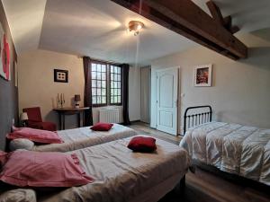 Braye-sous-FayeAux Acacias的一间卧室配有两张带红色枕头的床。