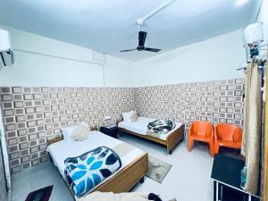 王舍城HOTEL RAJGIR INTERNATIONAL的一间客房配有两张床和两张橙色椅子