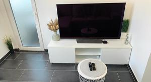 阿尔泽特河畔埃施Esch/Alzette city apartment的白色橱柜上的电视机,有凳子