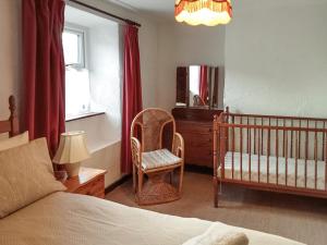 霍伊斯Gayle Farmhouse的一间卧室配有婴儿床、椅子和镜子