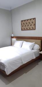 日惹Griya Sambilegi的一张配有白色床单和枕头的大床