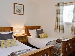 AuchnastankWoodside Cottage的一间卧室设有两张床和窗户。
