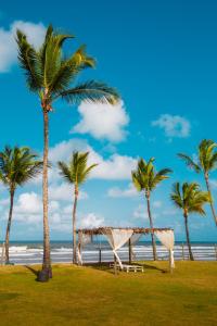 伊列乌斯花园艾特兰缇克海滩度假村的棕榈树海滩上的帐篷和大海