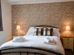 瓦利Yr Hen Feudy的一间卧室设有砖墙和一张床