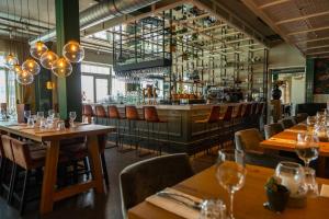 厄伊特丹Comfort Rooms & Appartments by EuroParcs Poort van Amsterdam的一间带木桌椅的餐厅和一间酒吧