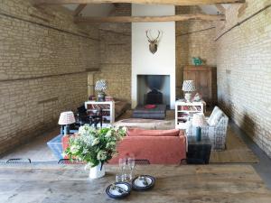 Ampney CrucisThe Cotswold Barn的客厅设有红色沙发和砖墙