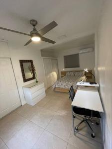 迈阿密Comfortable modern apartment- central location.的一间卧室配有一张床、一张桌子和吊扇