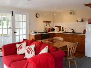 Bardon Mill菲尔布里奇度假屋的一间带红色沙发的客厅和一间厨房
