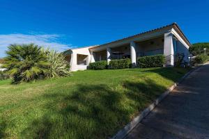 Grosseto-PrugnaBella Vista , à Porticcio, joli appartement vue mer的院子前有棕榈树的房子
