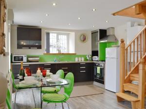 HendyLily Vale Cottage的厨房配有玻璃桌和绿色椅子