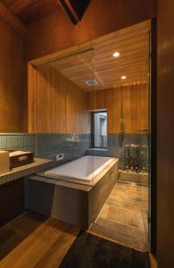 长滨市Hitoiki的大型浴室设有浴缸和淋浴。