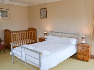 伊林港Windways的一间卧室配有一张带白色床单和一张婴儿床的床。
