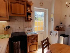 SwayLaurel Cottage的厨房配有炉灶、桌子和窗户。