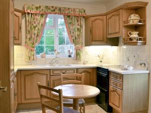 SwayLaurel Cottage的厨房配有木制橱柜、桌子和窗户。
