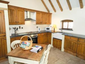 DunstallGrooms Cottage - E5398的厨房配有木制橱柜和木桌。