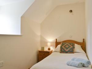 Llanrhaeadr-ym-Mochnant泰瑞德乡村别墅的一间卧室配有一张床和一张桌子上的台灯
