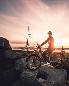 FeilitzschChalet-Ferienwohnung Sonnenidyll, 51 qm, Wellness/Fitness/Sauna – Bergrödelhof的骑着自行车在日落时分在岩石上骑行的人