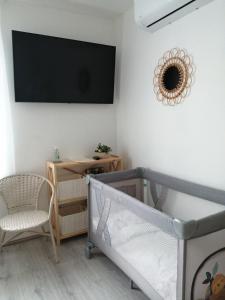 利耶帕亚PortStreet apartamenti的一间卧室配有婴儿床,墙上配有电视。