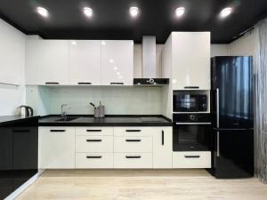 巴甫洛达尔Апартаменты LUX +的厨房配有白色橱柜和黑色冰箱。