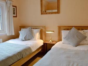Llanddona霍索恩乡村别墅的一间卧室设有两张床,墙上设有一面镜子