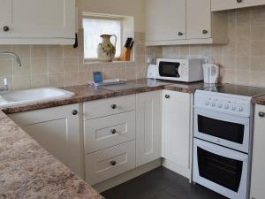 BemptonRockville Cottage - 24376的厨房配有白色橱柜、水槽和微波炉