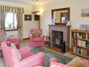 KilchenzieHazels Cottage的客厅配有红色椅子和壁炉
