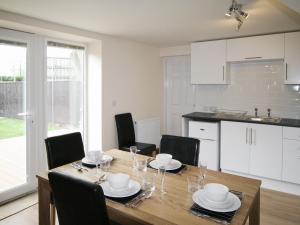 WinthorpeBarn Cottage - E5560的厨房以及带木桌和椅子的用餐室。