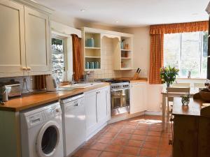 奇平卡姆登罗斯迎宾小屋的厨房配有白色橱柜、洗衣机和烘干机