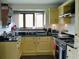 兰戈伦Bwthyn Clyd的厨房配有黄色橱柜和炉灶烤箱