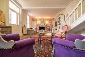 布尔日Le Cedre Bleu的客厅配有紫色椅子和壁炉