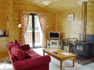 格勒尼斯拉基克顿Larch Cottage - S4428的客厅配有红色沙发和炉灶