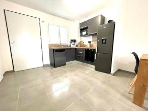 圣马迪拉莫Villa 8 personnes bord de mer climatisée的厨房配有黑色冰箱,铺有瓷砖地板。