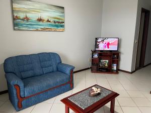 安谢塔Apartamento 3 quartos Beira Mar的客厅配有蓝色的沙发和电视