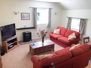 Kniveton奶品乡村别墅的客厅配有2张红色沙发和1台电视
