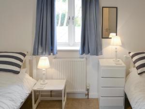 RoughtonThe Boat House的一间卧室设有两张床,窗户配有蓝色窗帘
