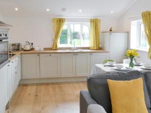 RoughtonThe Boat House的厨房配有白色橱柜和带黄色枕头的桌子。
