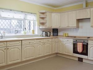 基尔格蒂绿色英亩度假屋的厨房配有白色橱柜、水槽和窗户。