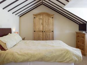 基尔格蒂绿色英亩度假屋的一间卧室配有一张大床和一个木制橱柜