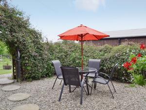 StaintondaleCart Cottage - 28343的一张桌子和椅子,配有红色雨伞