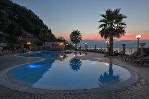 罗迪-加尔加尼科特拉蒙托公寓式酒店的一座棕榈树和日落的大型游泳池