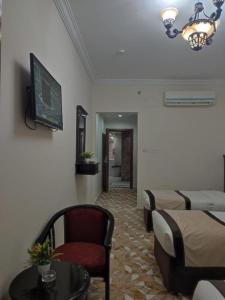 Al ‘Azīzīyahاوتاد المتحدة的客房设有两张床、一张桌子和一台电视机。
