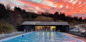 博尔加内斯Mófellsstaðakot的一座享有日落美景的建筑前的游泳池
