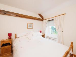 克罗索恩Holly Cottage的卧室配有白色的床和窗户。
